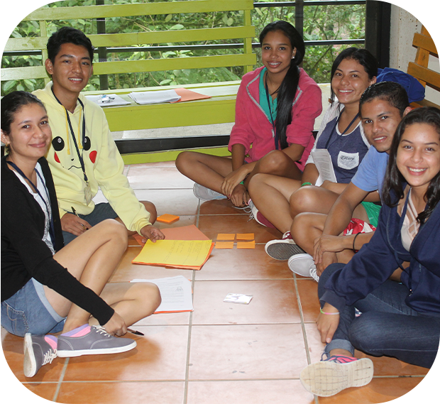 adolescentes sentados en el piso, están sonriendo y trabajando con papel